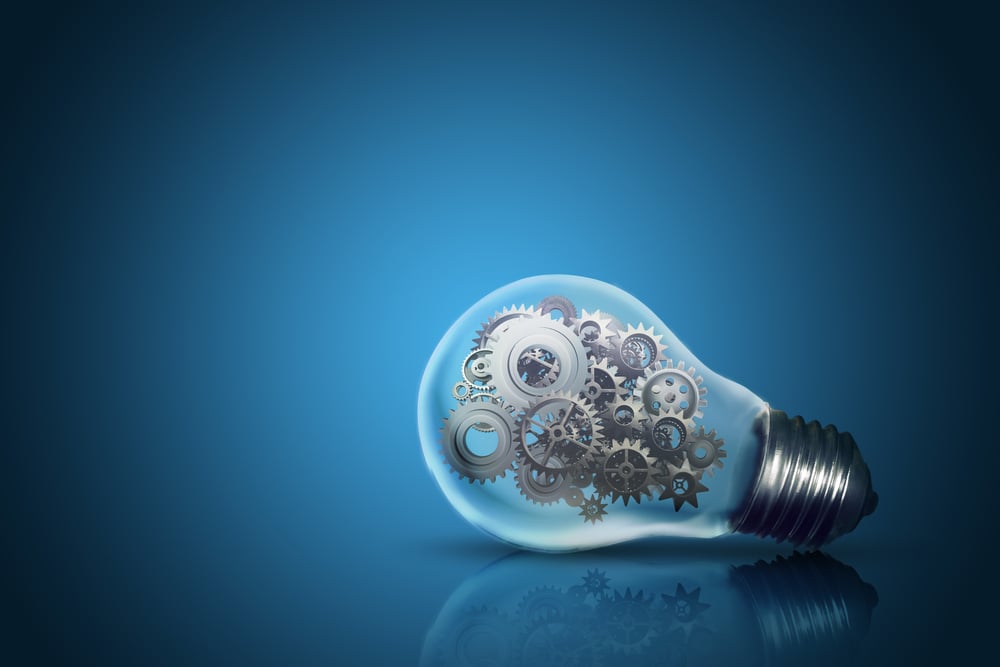 Image Close up of light bulb with gear mechanism inside isolated on dark blue background